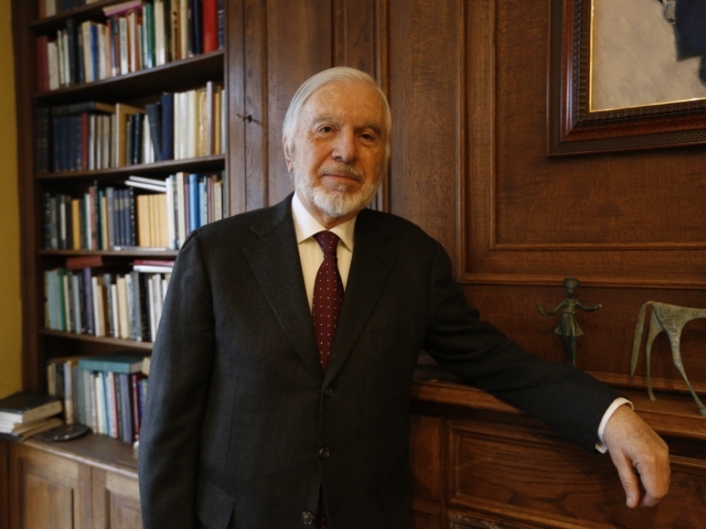 Profesor titular emérito Oscar Godoy. En el fondo un estante con libros 